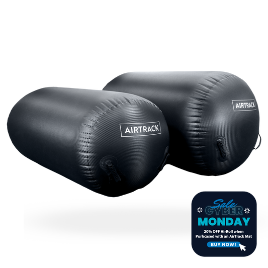 Two black inflatable gymnastics barrels with 'AIRTRACK' branding, featuring a Cyber Monday sale banner.